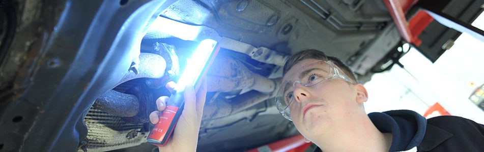 Motor Vehicle student underneath a car